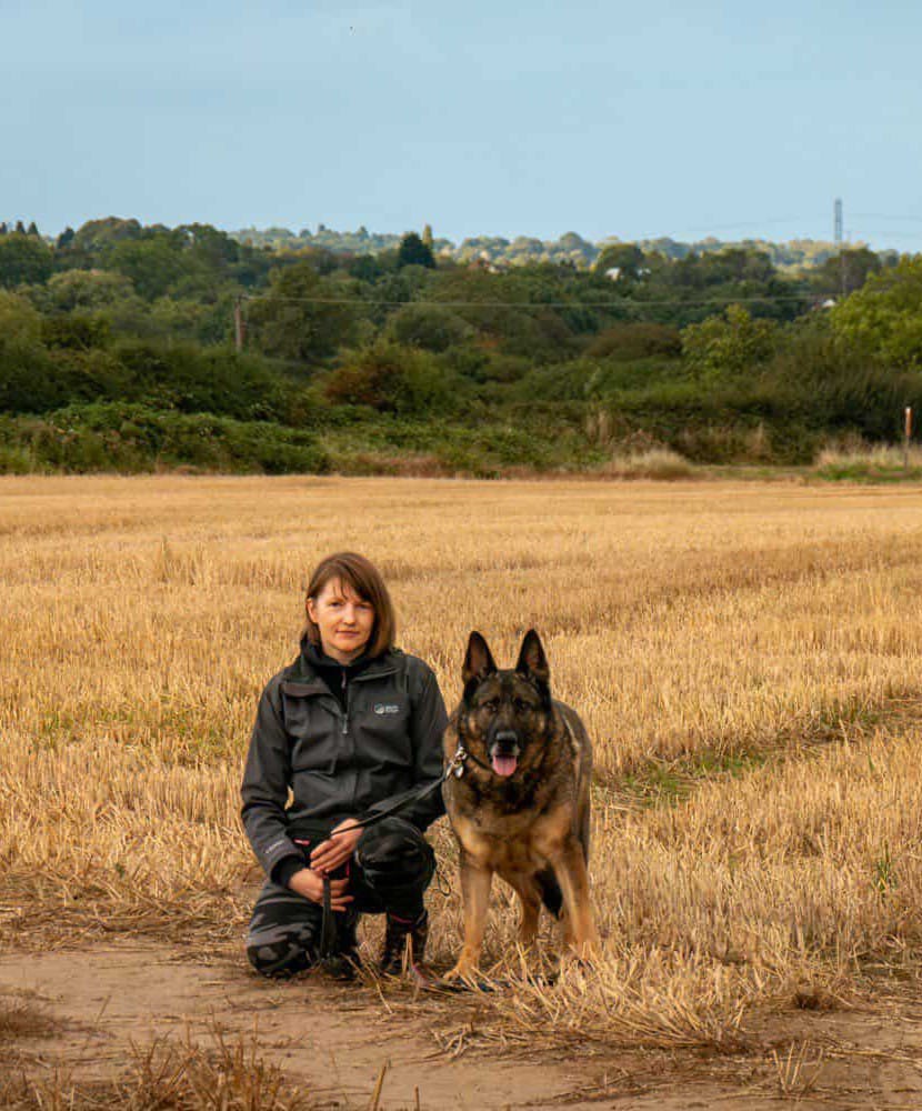 Kristine Graham kneeling in a field with a German Shepherd